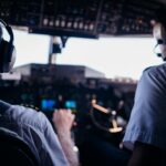 Back view of anonymous male pilots in uniform and headset navigating modern airplane while taking off